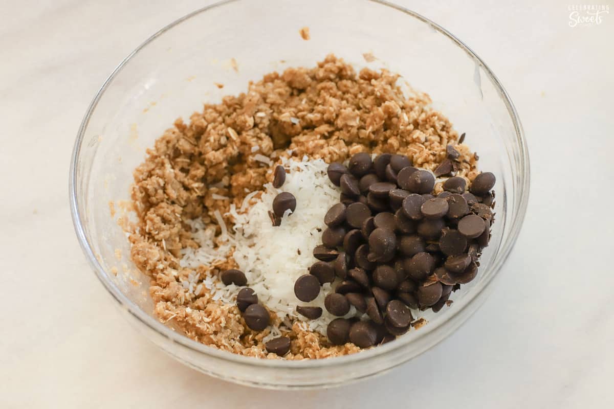 Cookie dough, chocolate chips, and coconut in a glass bowl.