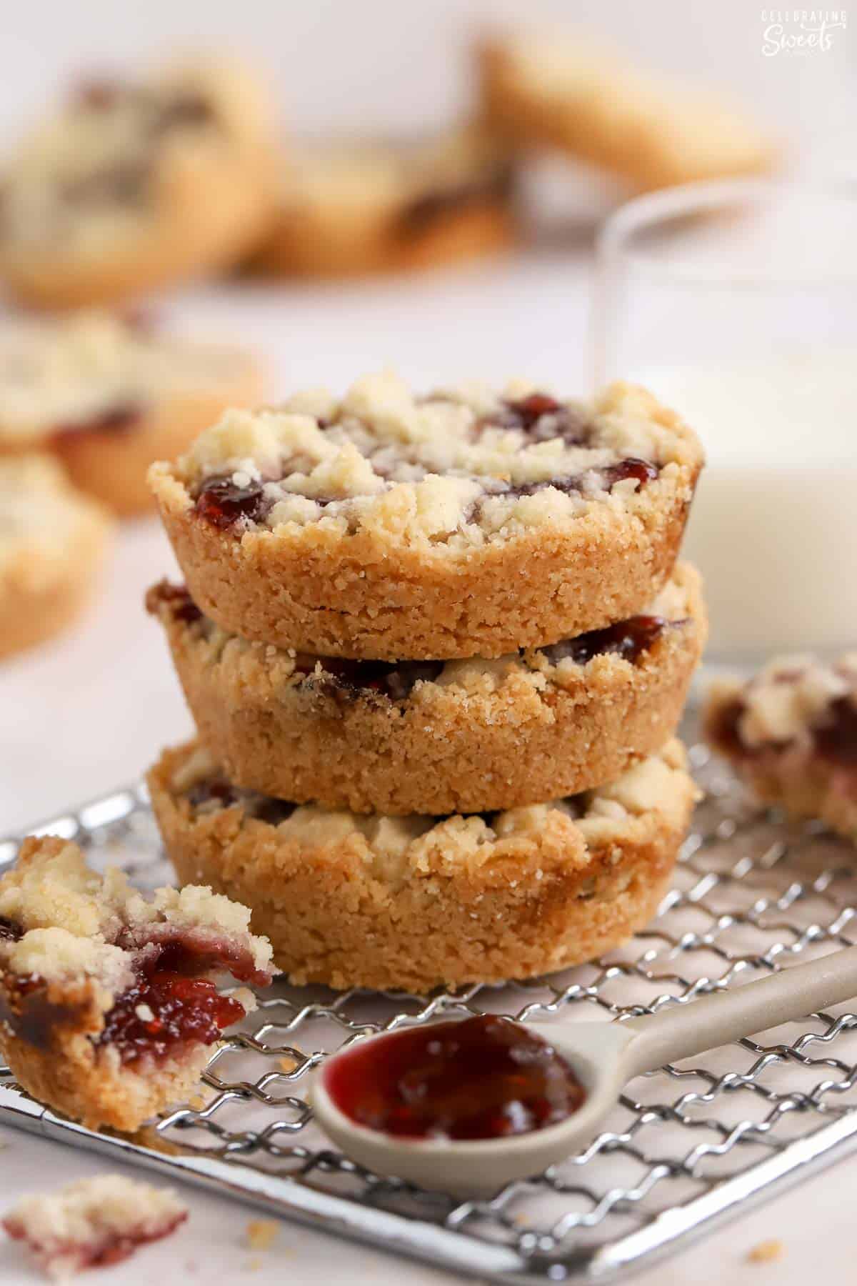 Stack of three raspberry crumble cookies on a wire rack.