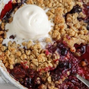 Berry crisp topped with ice cream in a baking dish.