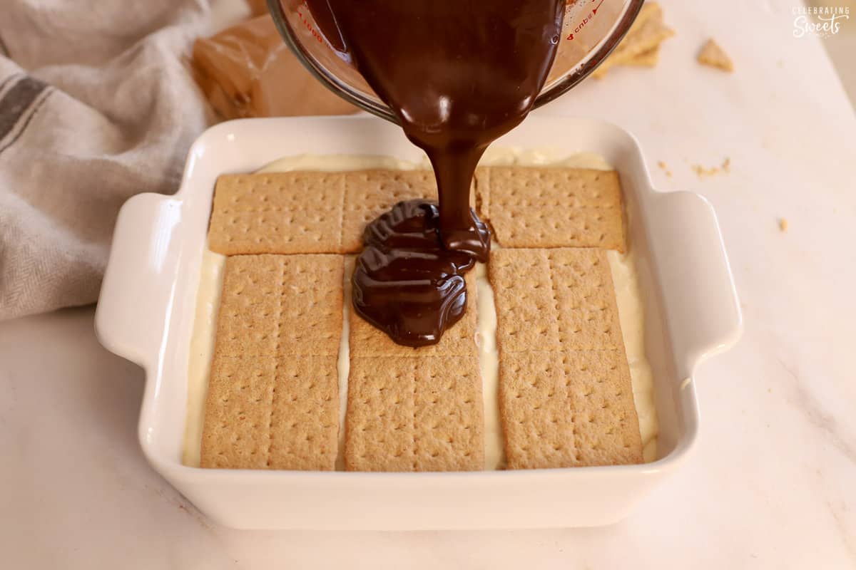 Chocolate ganache poured over graham cracker in a baking dish.