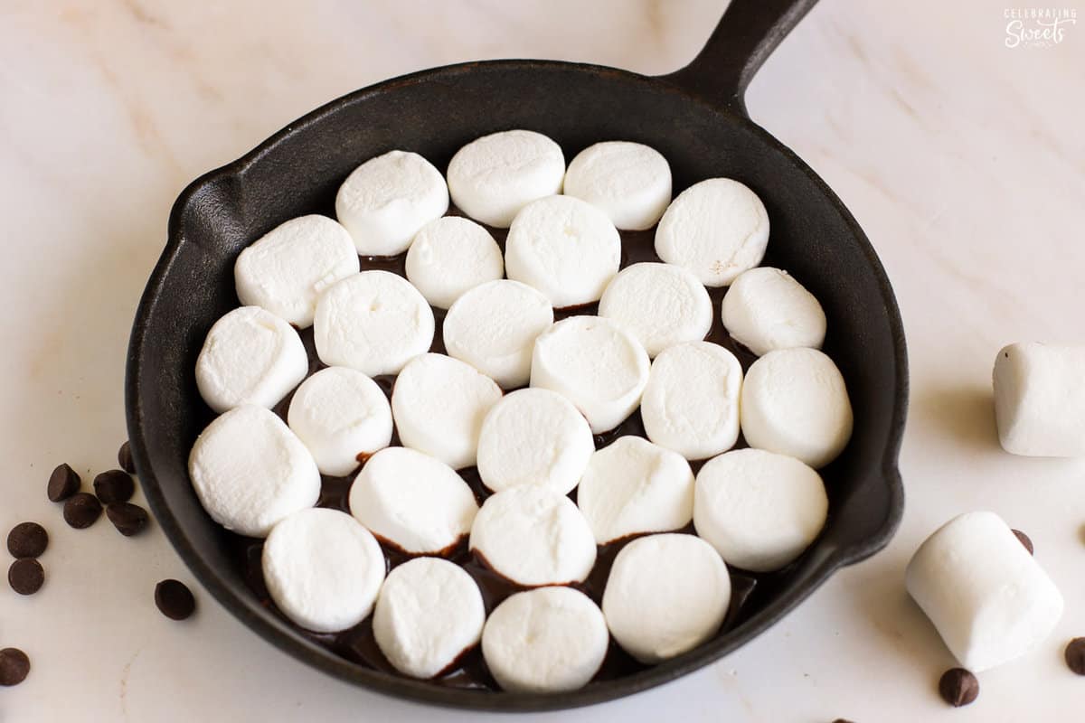 Marshmallows and melted chocolate in a cast iron skillet.