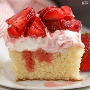Slice of strawberry shortcake cake on a white plate.