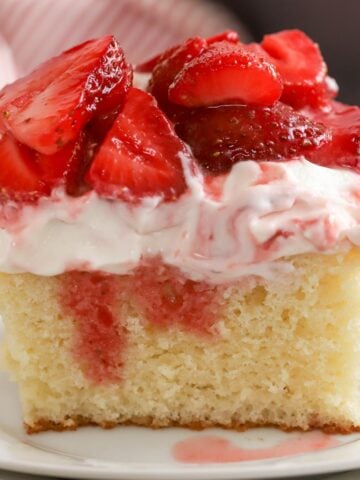 Slice of strawberry shortcake cake on a white plate.