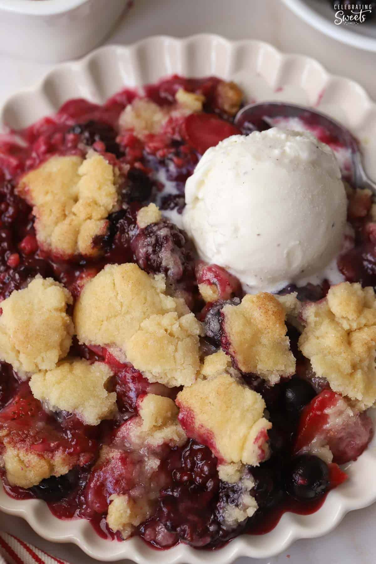Closeup of berry cobbler with a scoop of vanilla ice cream.