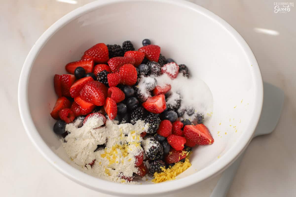 Berries, flour, lemon zest, and sugar in a large white bowl.