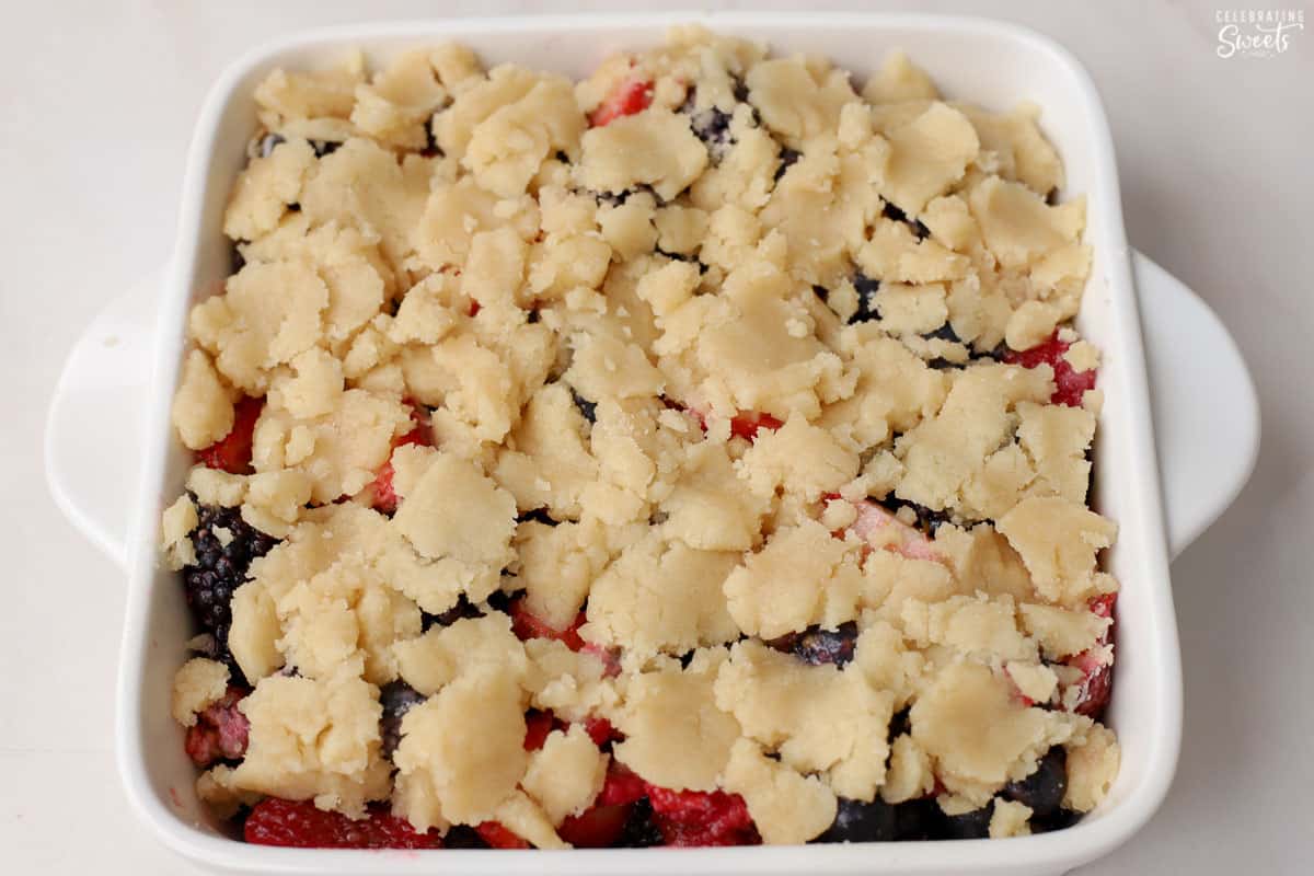 Unbaked berry cobbler in a white baking dish.