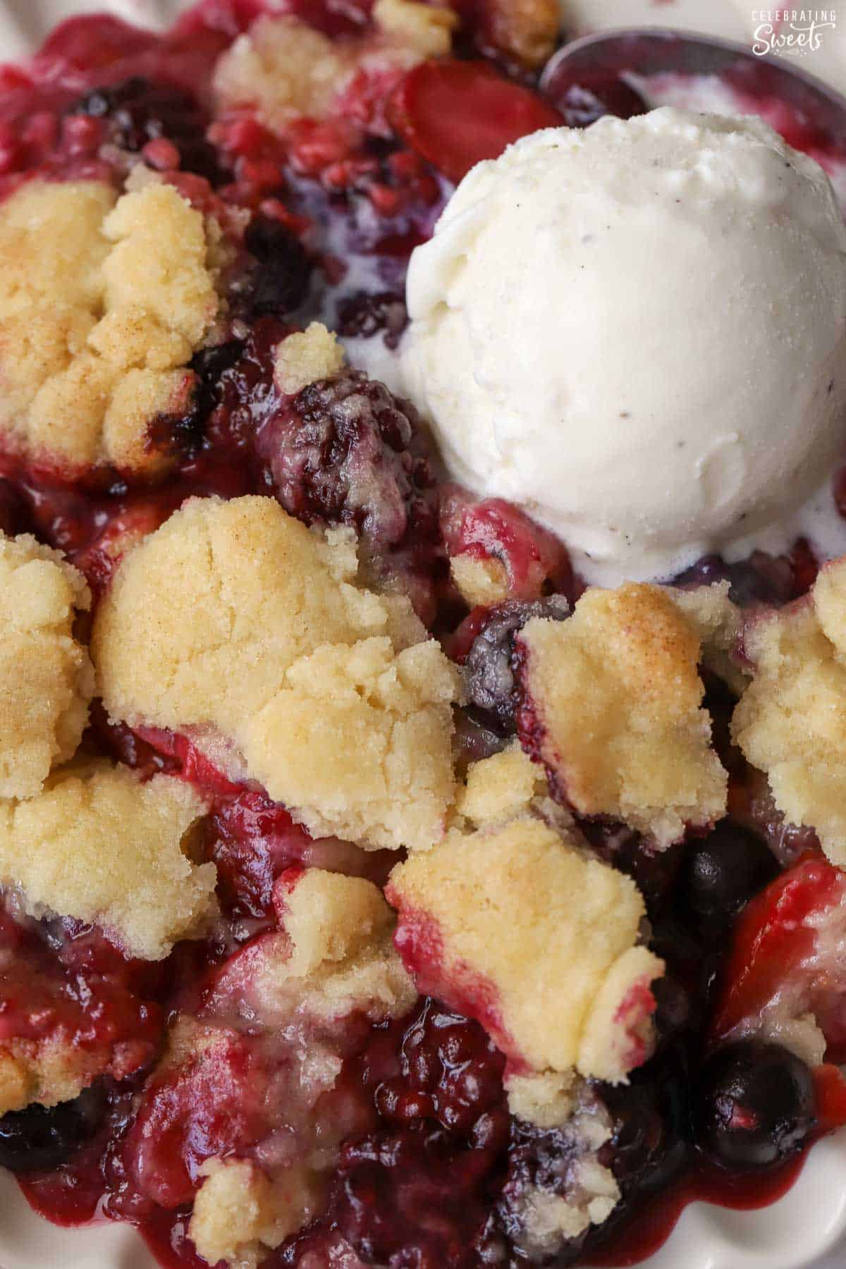 Closeup of berry cobbler topped with vanilla ice cream.