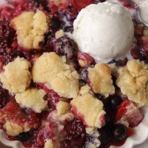 Closeup of berry cobbler with a scoop of vanilla ice cream.