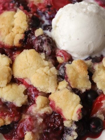 Closeup of berry cobbler with a scoop of vanilla ice cream.