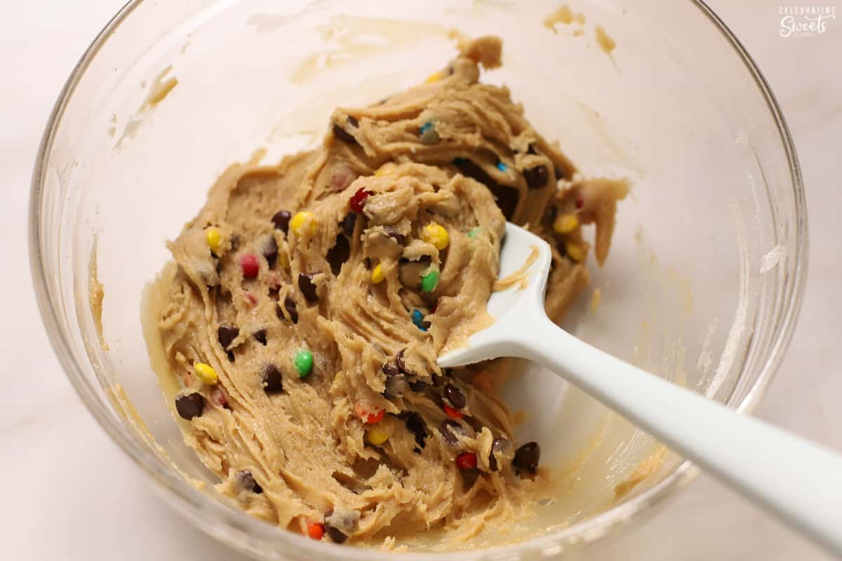 Cookie dough in a glass bowl filled with m&m's