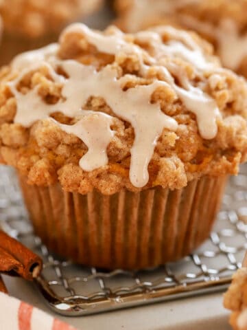 Closeup of a pumpkin muffin on a wire rack topped with icing.