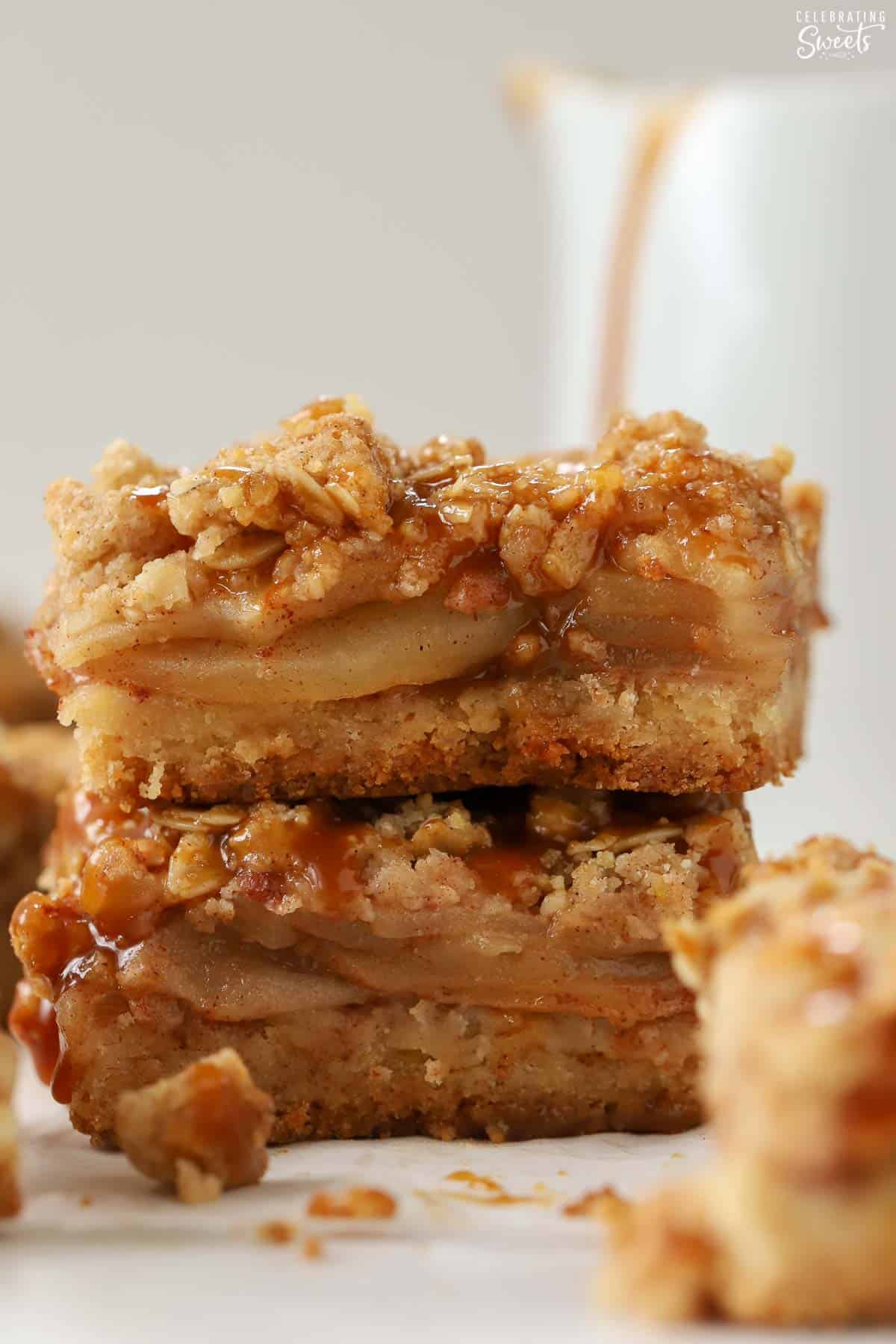 Stack of two apple crumb bars topped with caramel sauce.