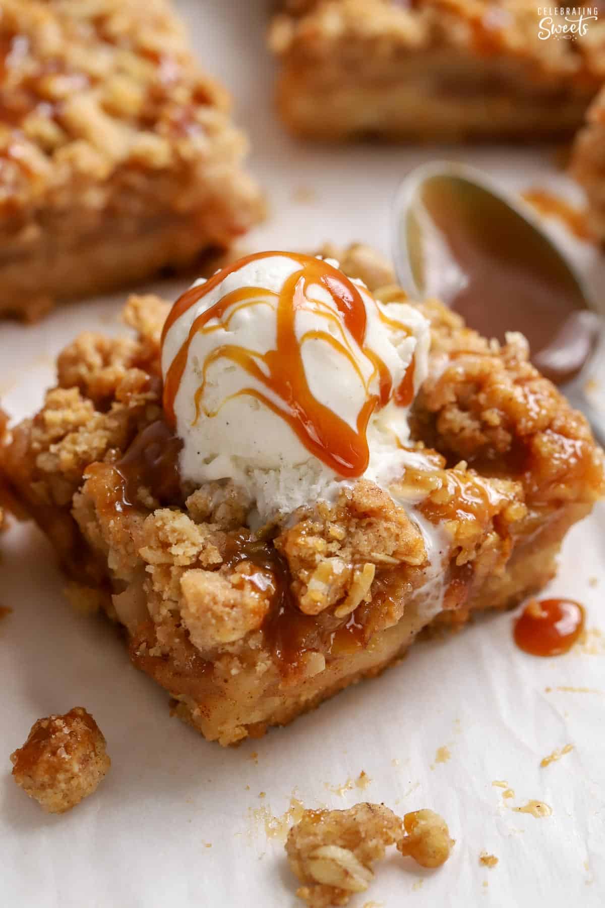 Apple crumb bar topped with a scoop of vanilla ice cream and caramel sauce.