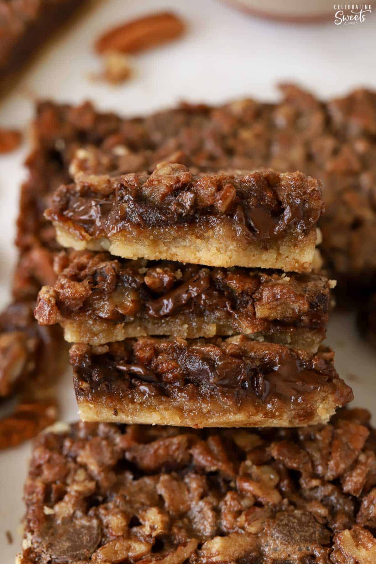 Three pieces of chocolate pecan pie bars stacked on top of each other.