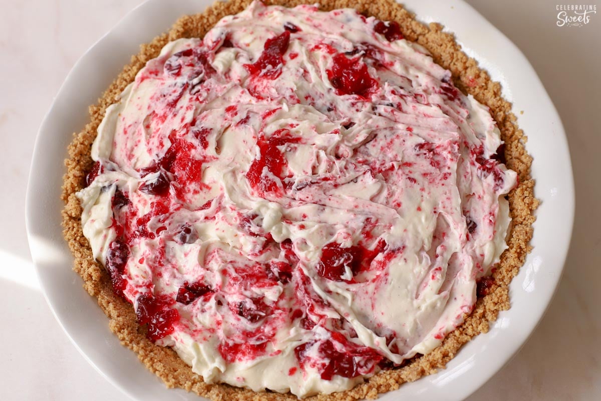 Cranberry cheesecake in a white pie dish.
