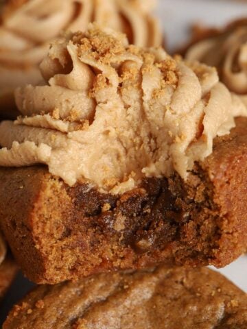 Gingerbread cookie cup topped with light brown frosting with a bite taken out of it.