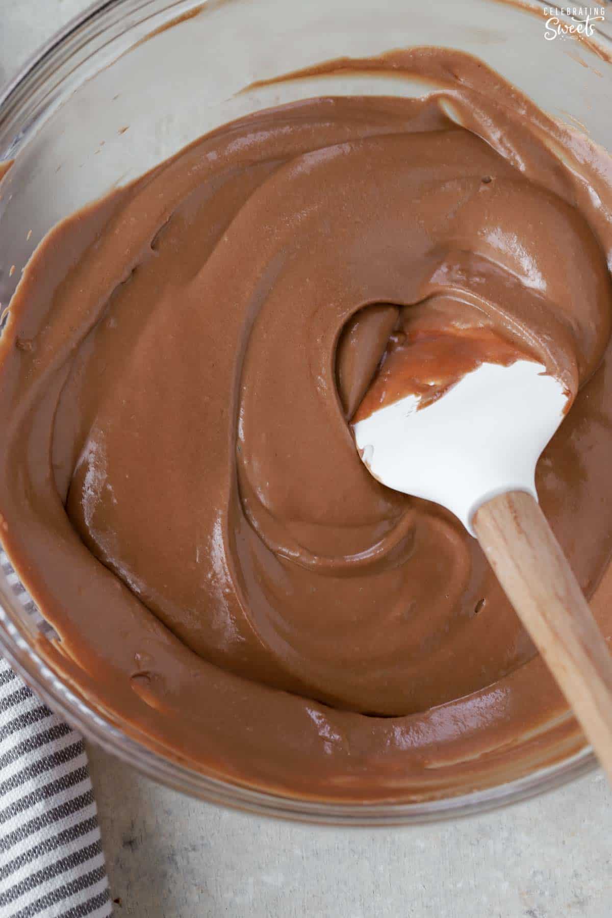 Creamy chocolate mousse in a glass bowl with a white spatula.