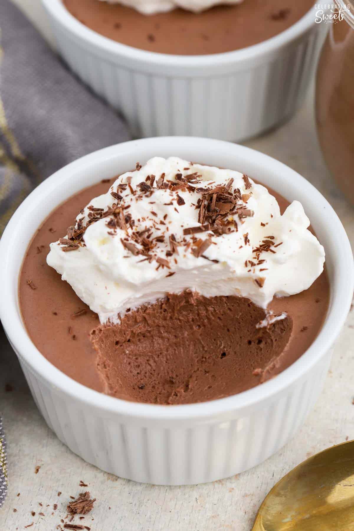 Chocolate mousse in a white ramekin topped with whipped cream.
