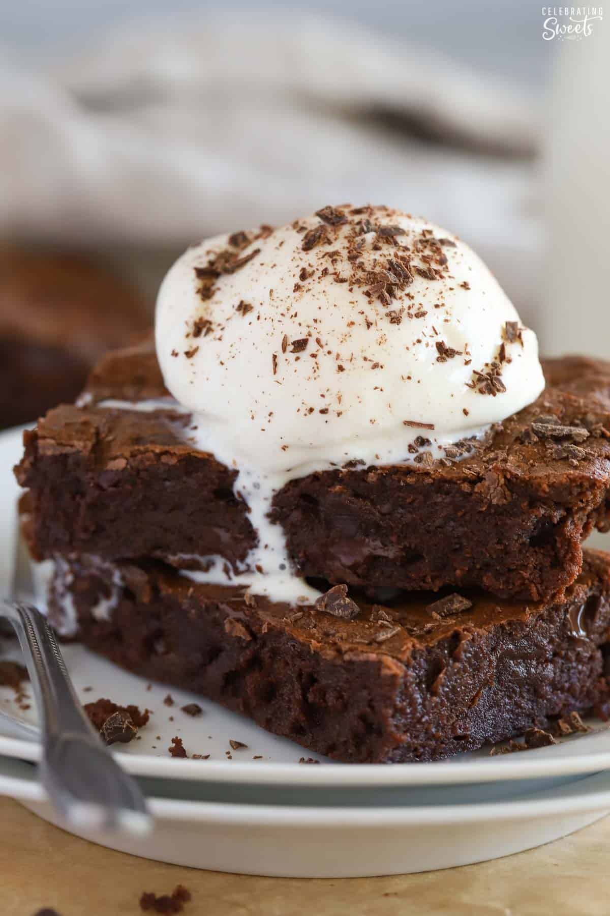 Stack of two brownies topped with vanilla ice cream.
