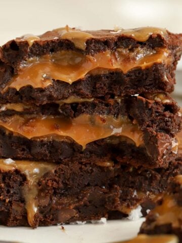 Stack of three caramel brownies on parchment paper.