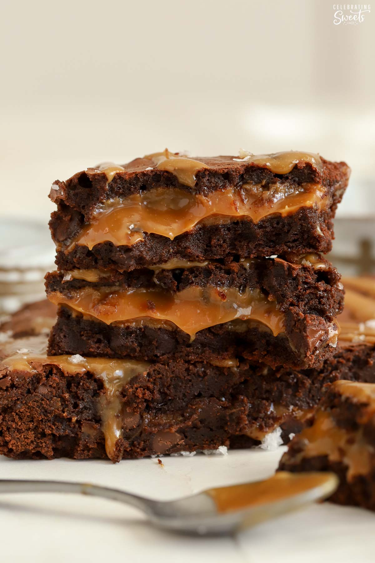 Stack of three caramel brownies on parchment paper.