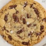Closeup of a large chocolate chip cookie on a parchment lined baking sheet.