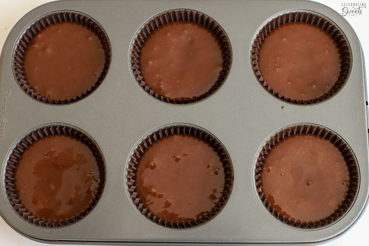 Chocolate cake batter in a 6-count muffin pan.