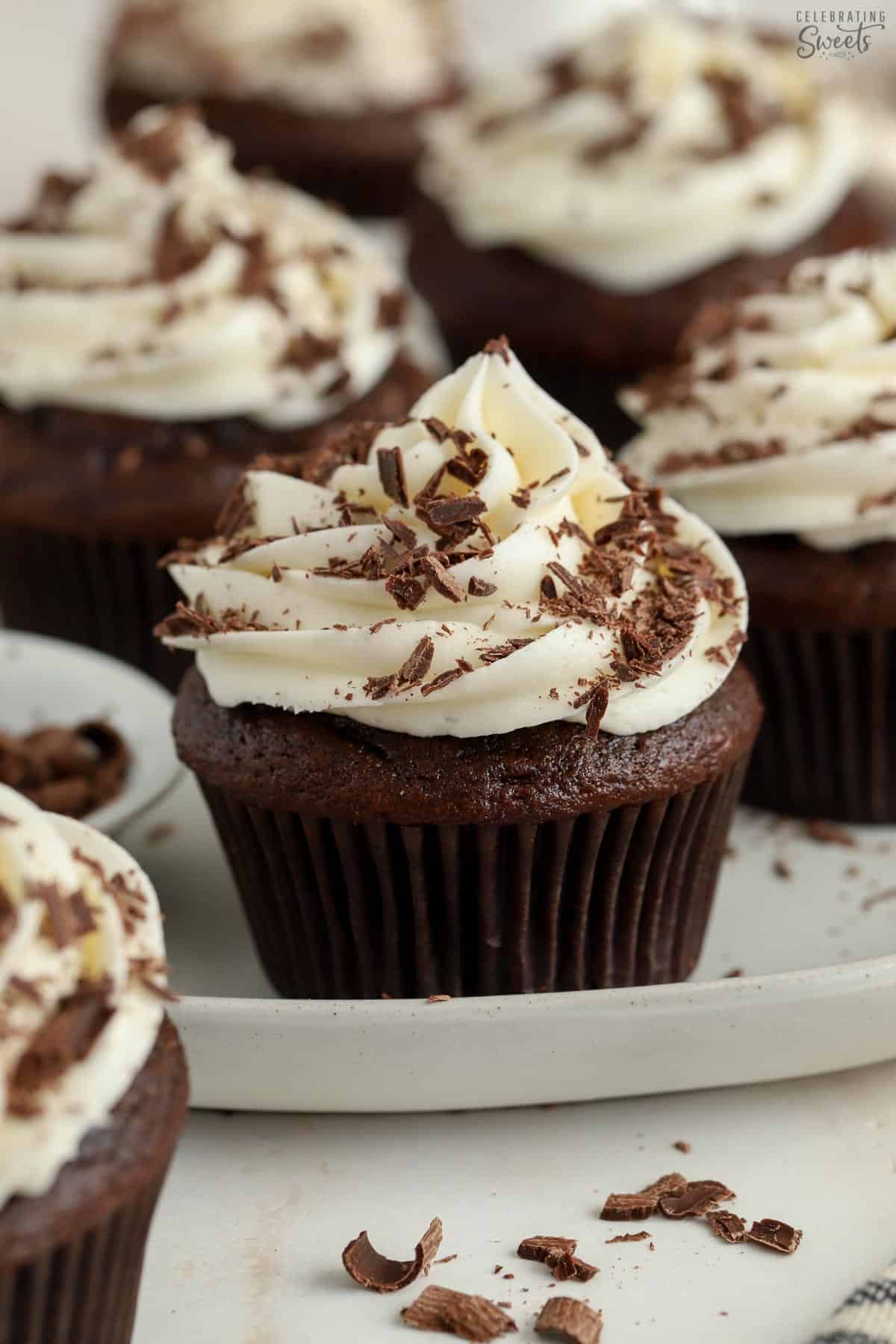 Chocolate cupcake topped with white frosting and chocolate shavings.