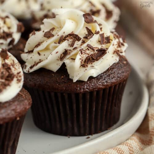 Chocolate cupcake topped with white frosting and chocolate shavings.