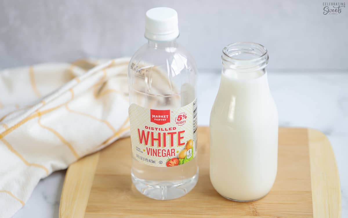 Buttermilk substitute and a jar of vinegar on a wooden board.