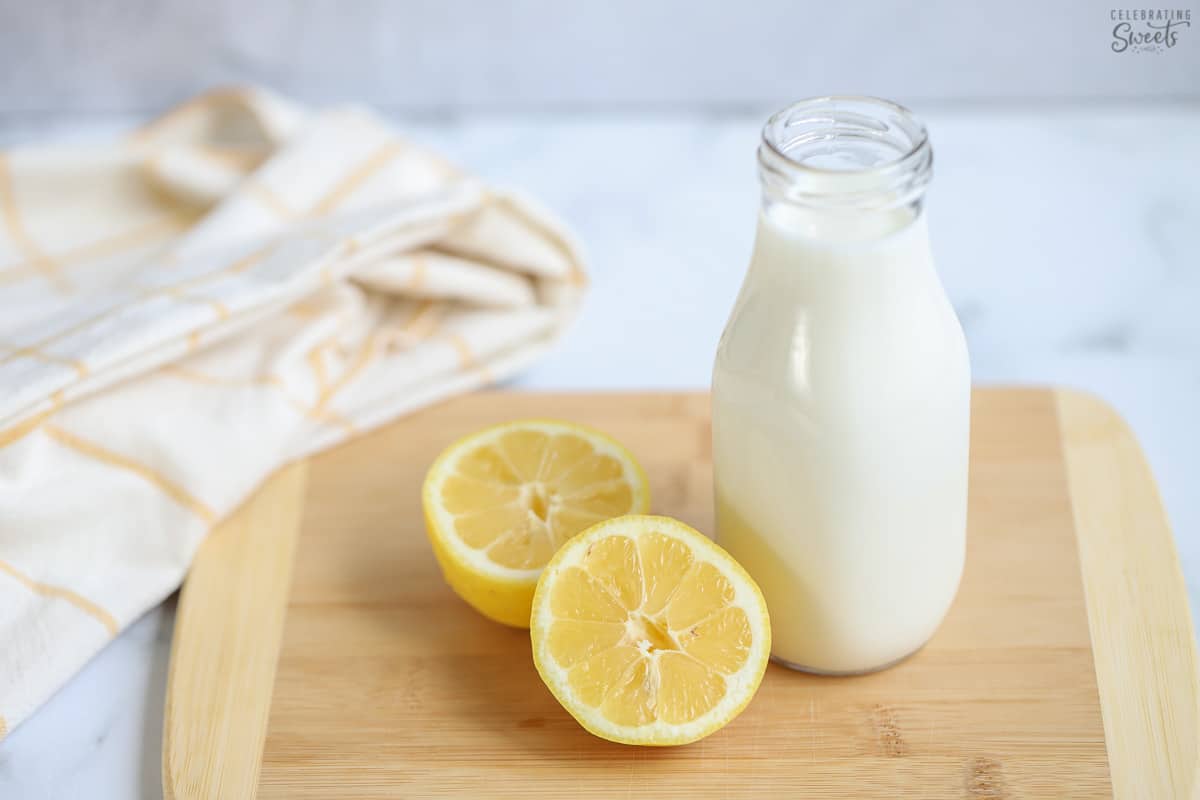 Buttermilk substitute and two lemons on a wooden board.