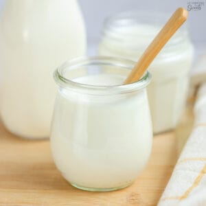 Jar of buttermilk substitute on a wooden board with a wooden spoon.