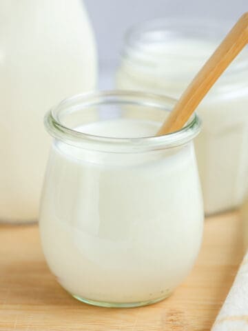 Jar of buttermilk substitute on a wooden board with a wooden spoon.