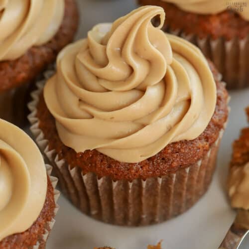 Carrot cake cupcake topped with swirled brown sugar frosting on a grey plate.