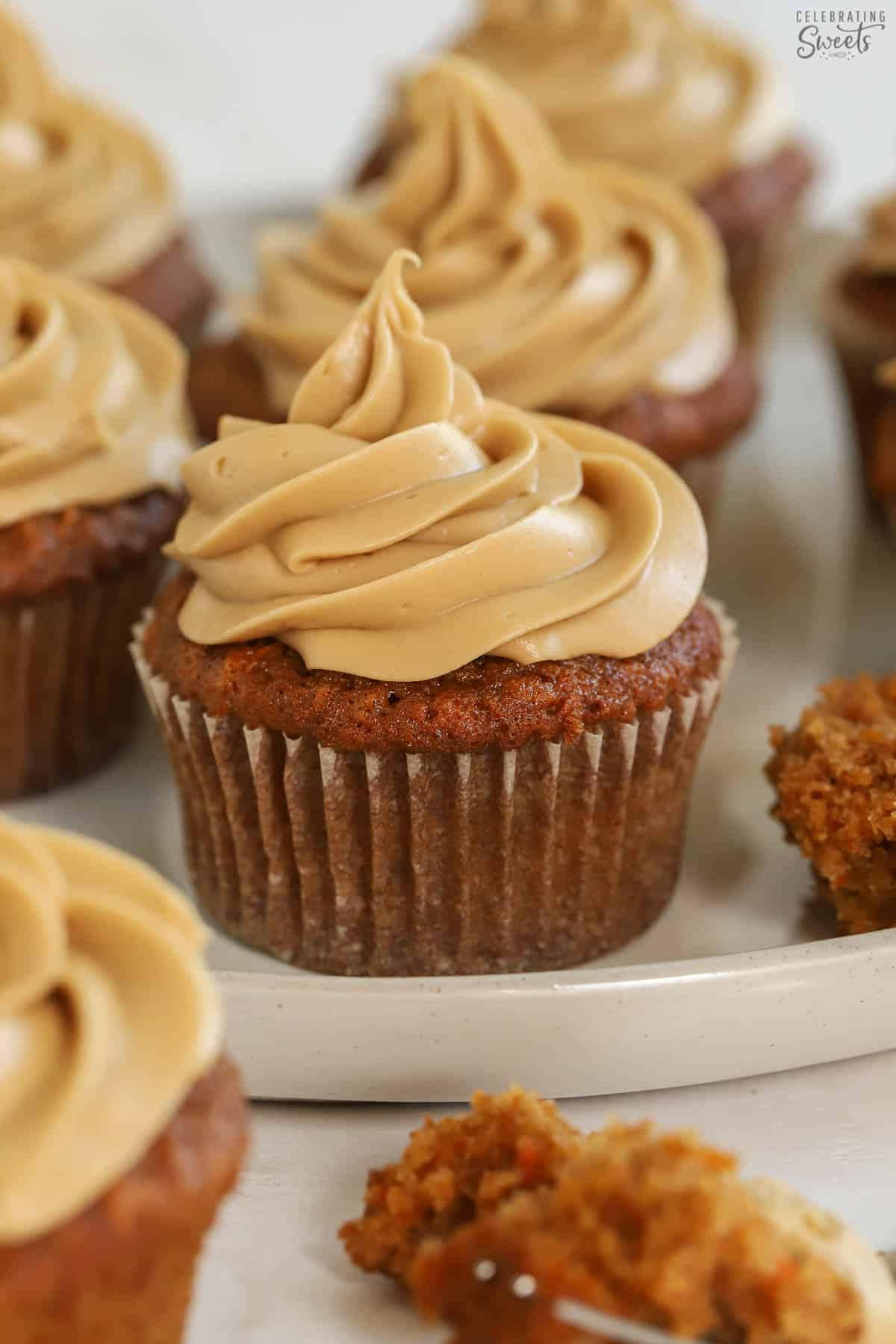 Carrot cake cupcake topped with brown sugar frosting on a grey plate.