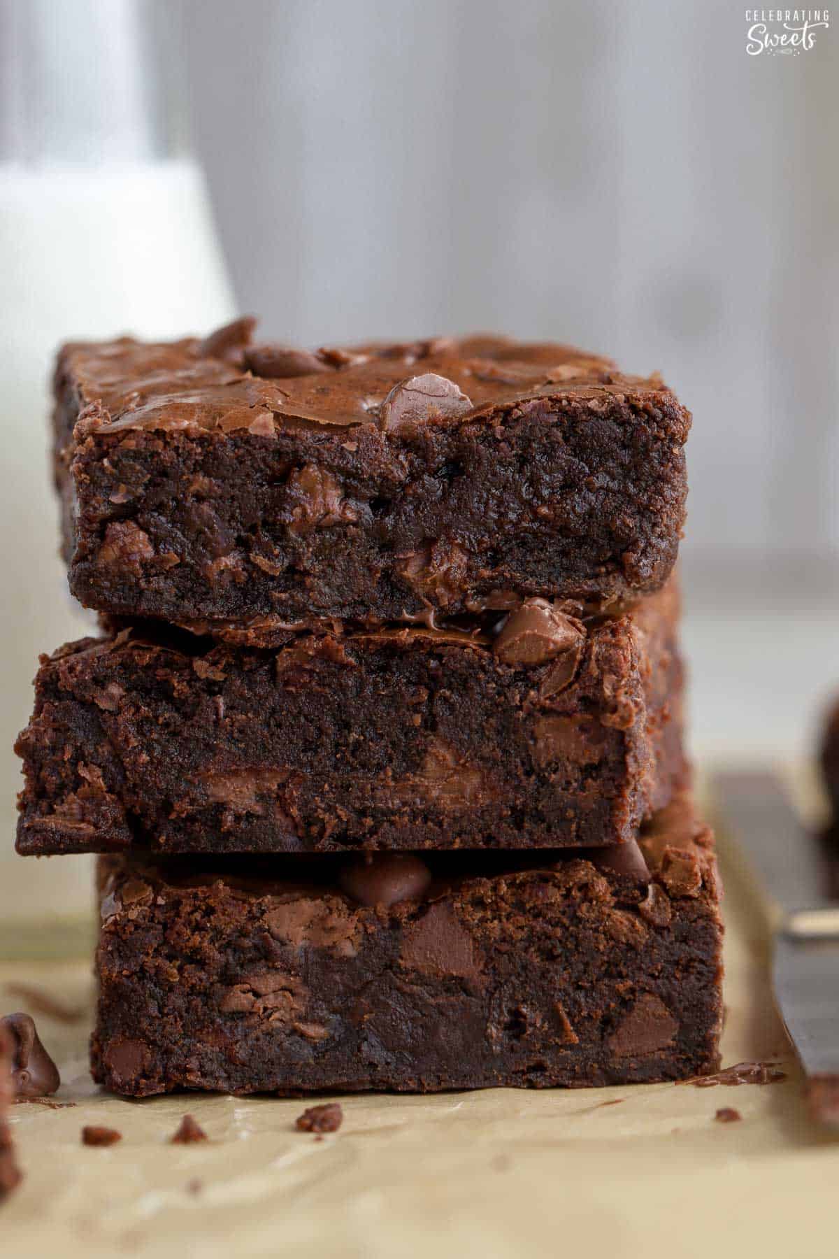 Stack of three homemade brownies on parchment paper.