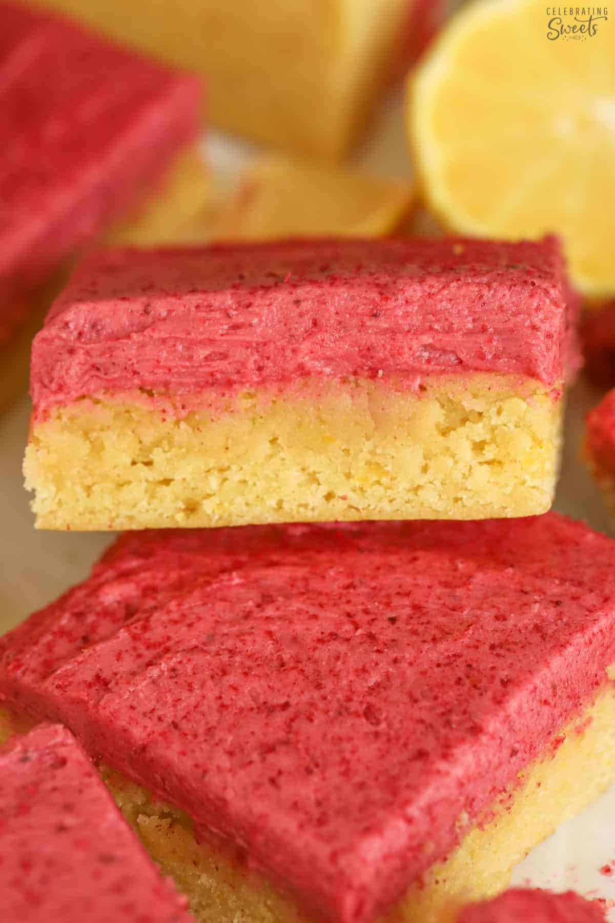 Closeup of a lemon bar topped with pink frosting.