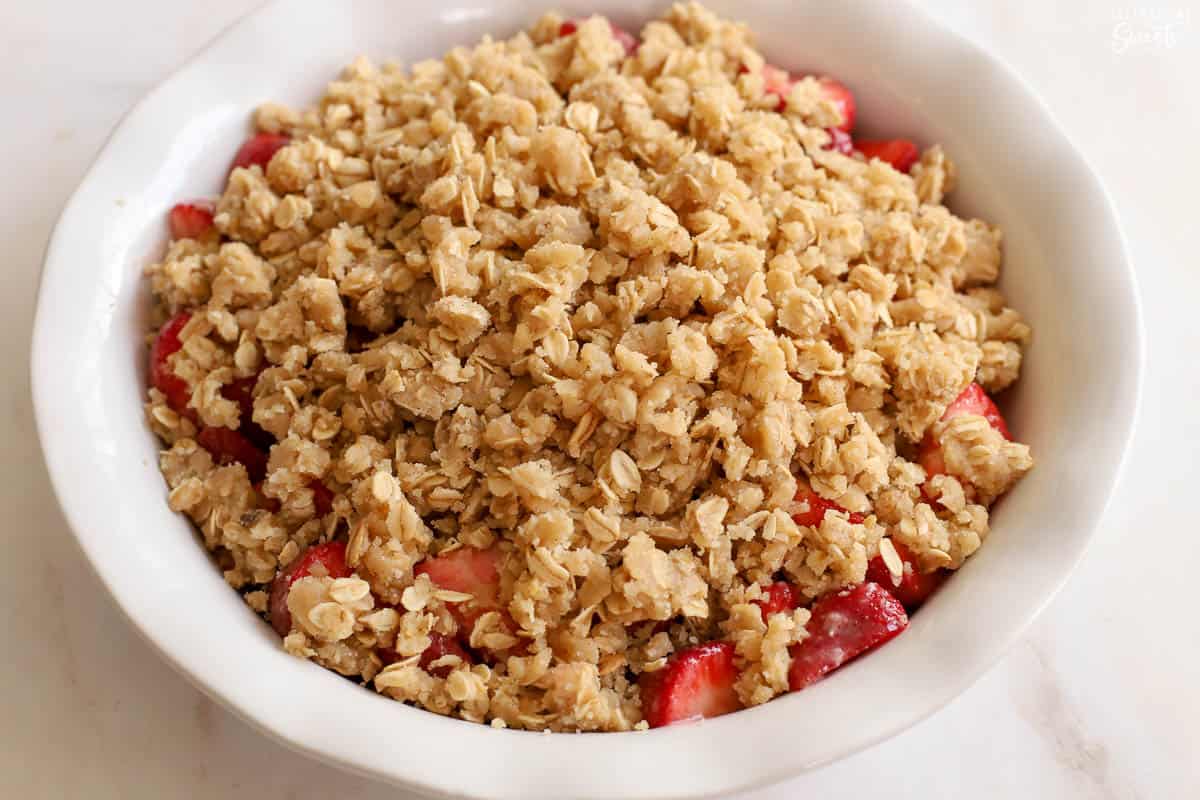 Unbaked strawberry crisp in a white baking dish.