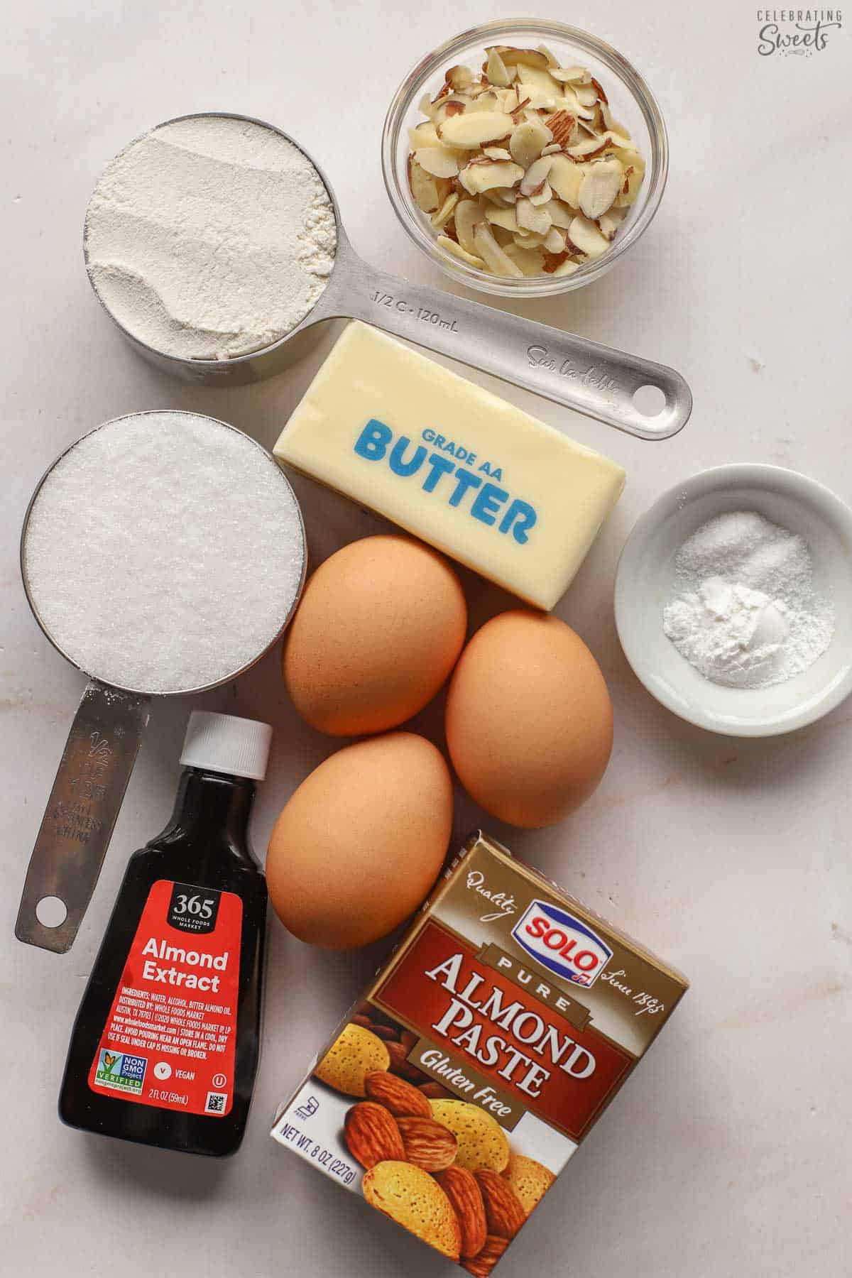 Ingredients for an almond cake: almond paste, almond extract, flour, sugar, eggs, butter, sliced almonds.