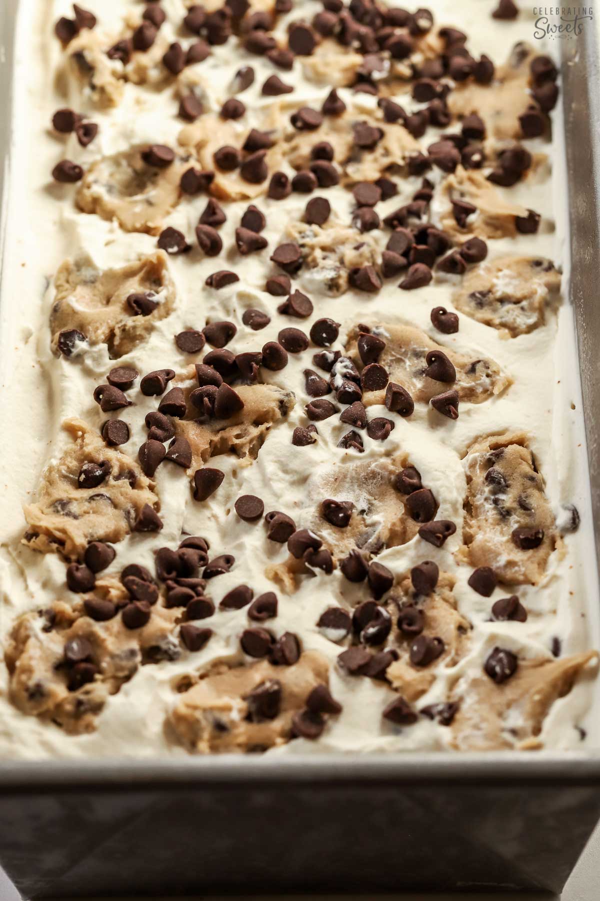 Closeup of chocolate chip cookie dough ice cream in a metal loaf pan.