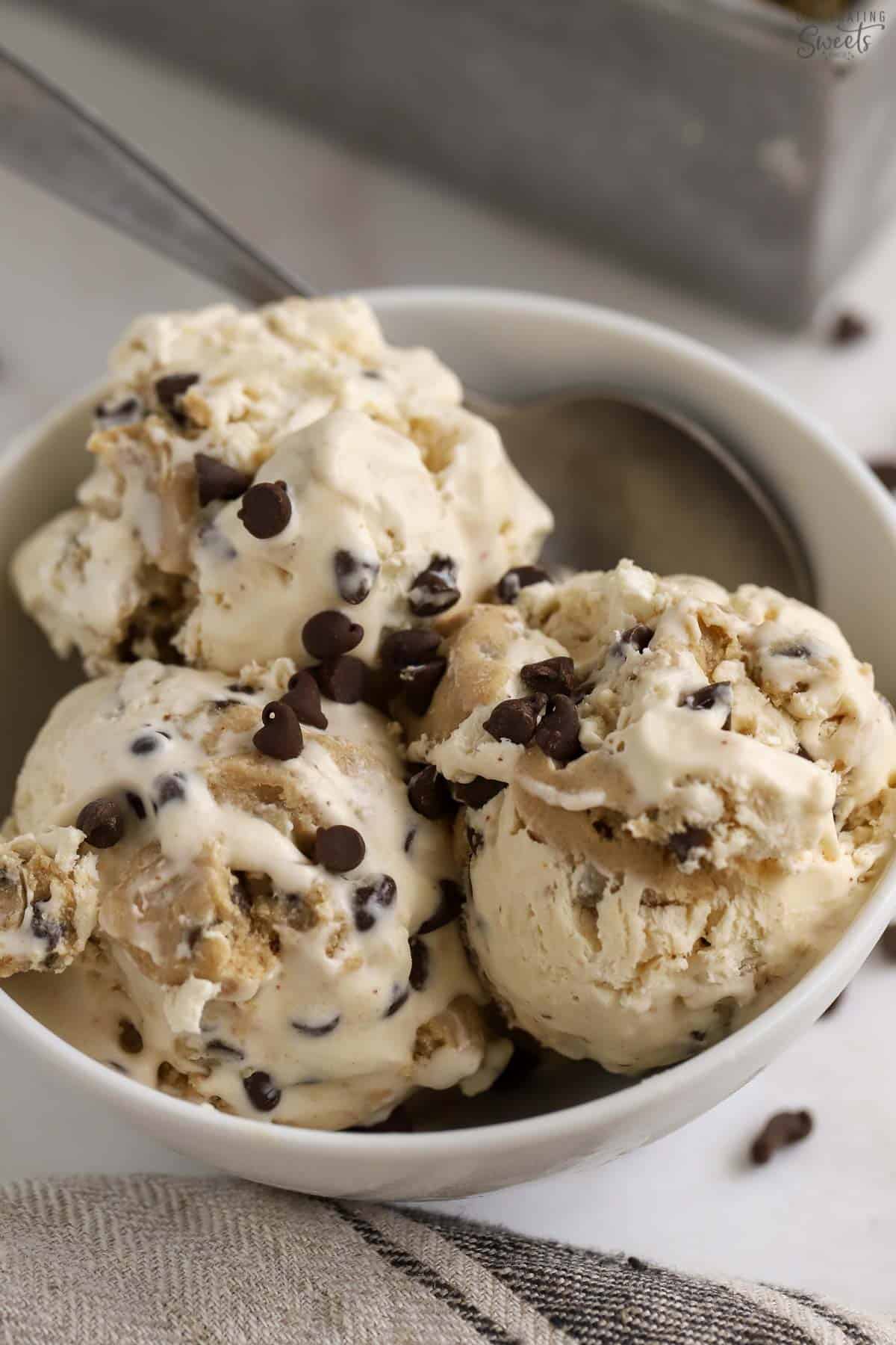 Three scoops of cookie dough ice cream in a white bowl.