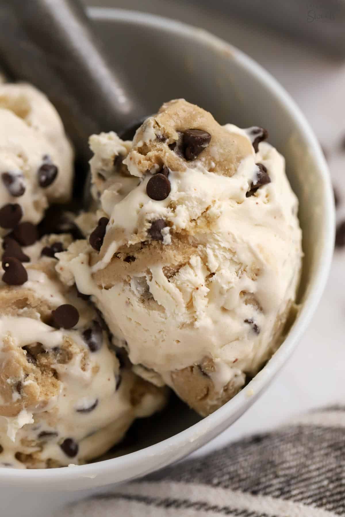 Closeup of a scoop of cookie dough ice cream in a white bowl.