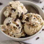Three scoops of cookie dough ice cream in a white bowl.