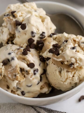 Three scoops of cookie dough ice cream in a white bowl.