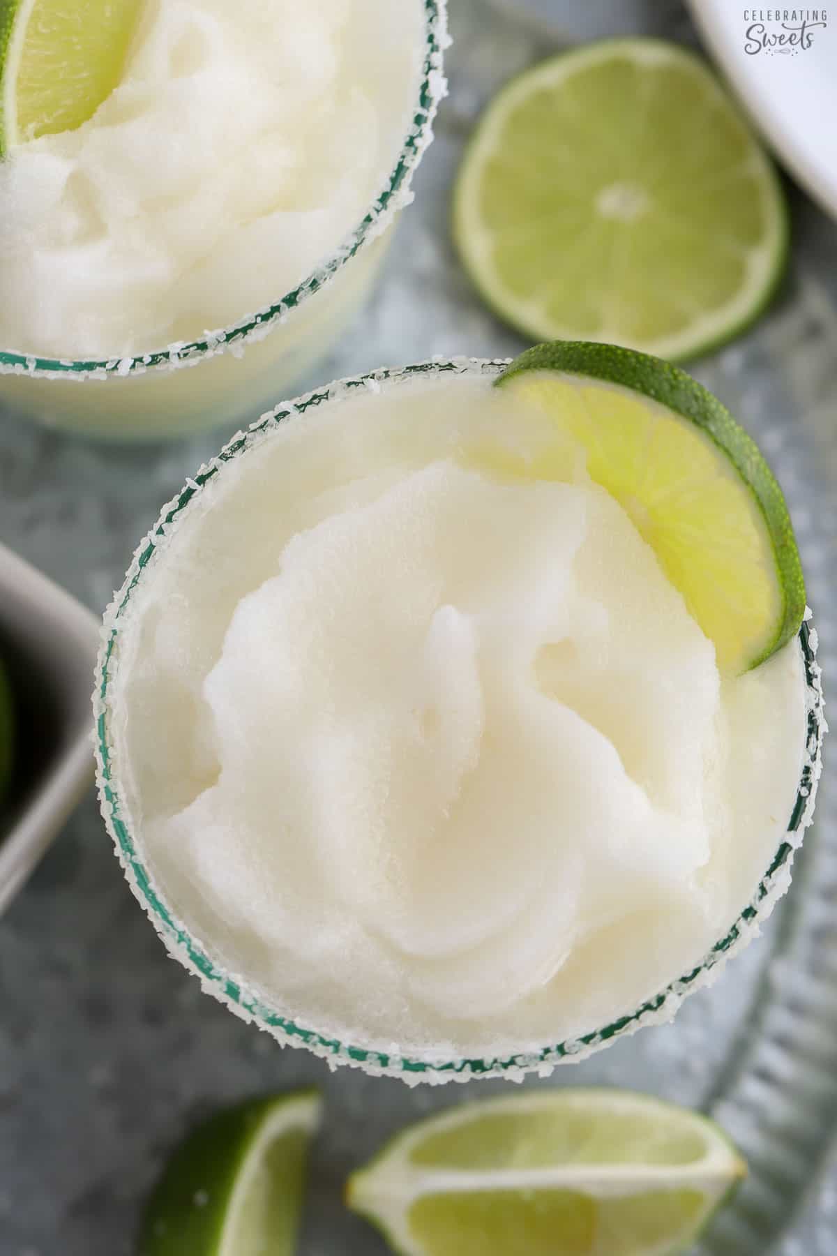 Frozen margarita in a glass garnished with lime.