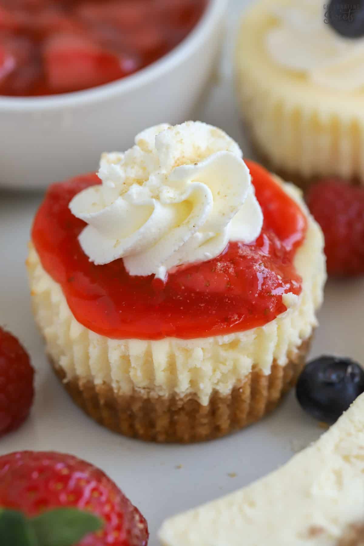 Mini cheesecake topped with strawberry sauce and whipped cream.