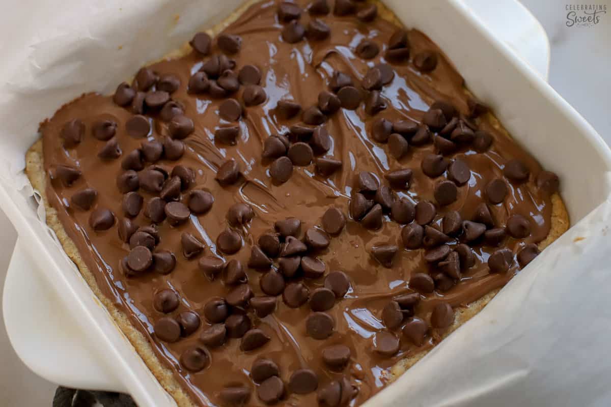 Nutella and chocolate chips on a cookie bar in a white baking dish.