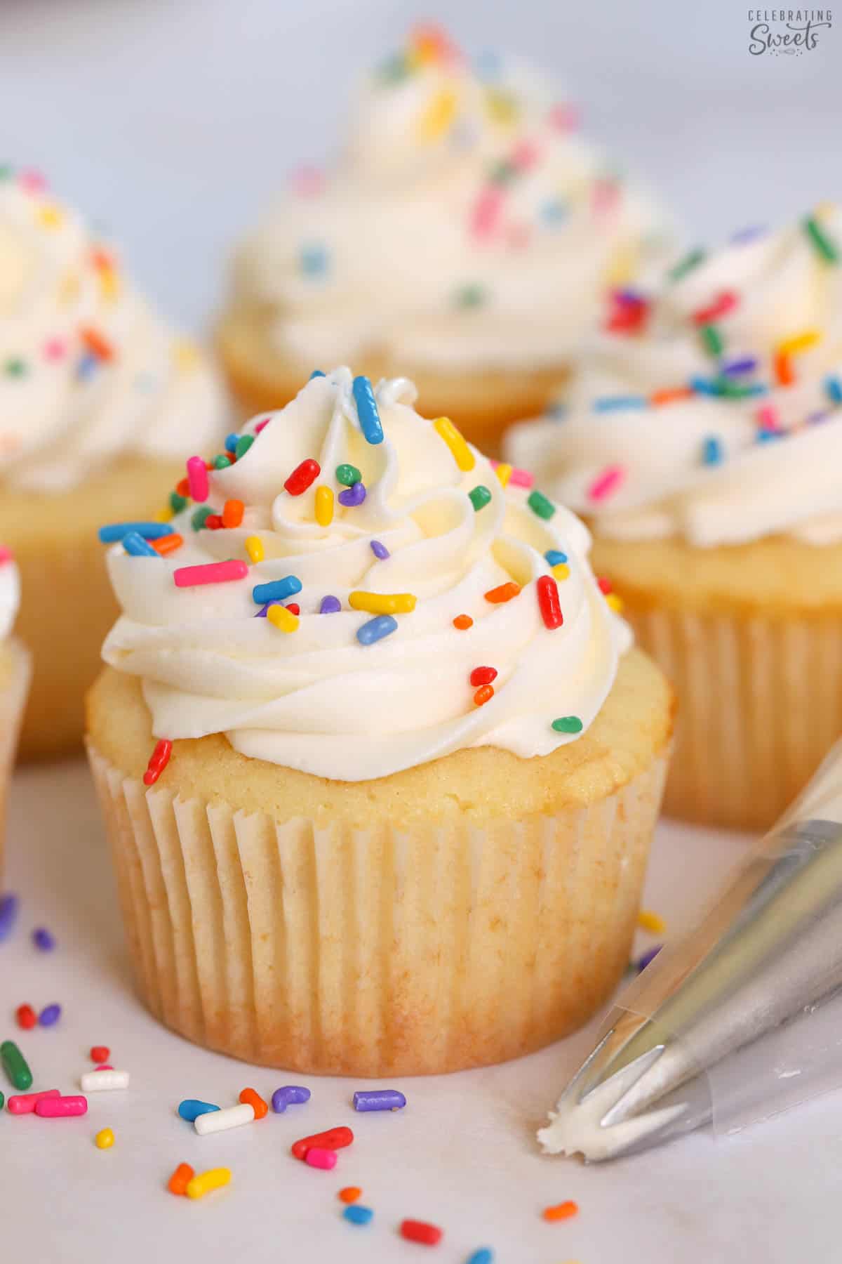 Small batch vanilla cupcakes topped with white frosting and rainbow sprinkles.