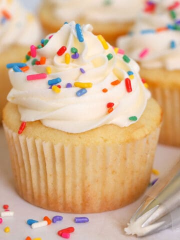 Small batch vanilla cupcakes topped with white frosting and sprinkles.