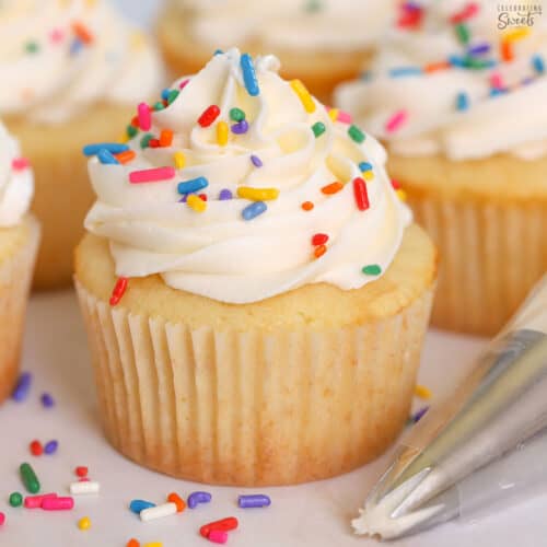 Small batch vanilla cupcakes topped with white frosting and sprinkles.